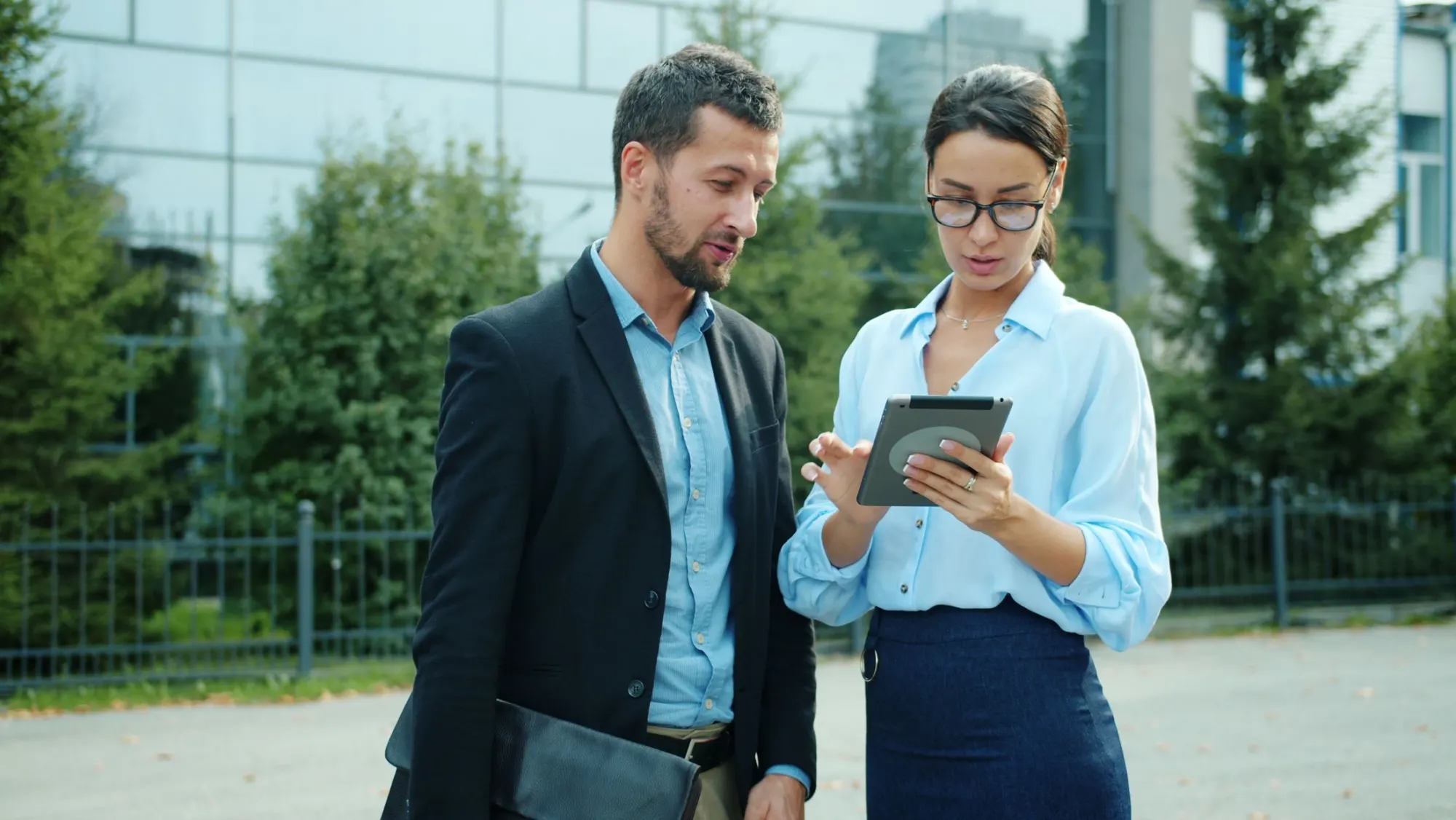 Colleagues discussing work on a tablet outdoors