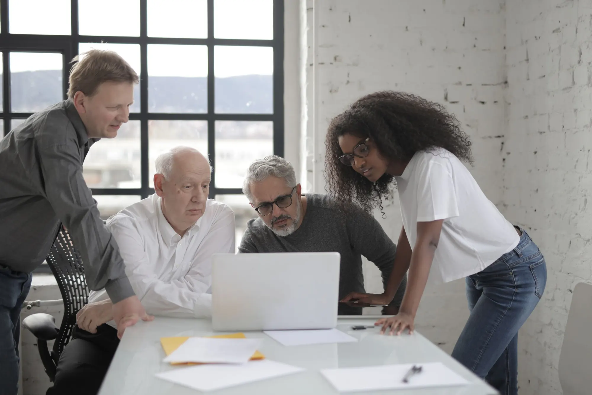 Colleagues collaborating around a laptop in a bright office